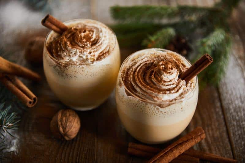 eggnog cocktails with whipped cream and cinnamon sticks
