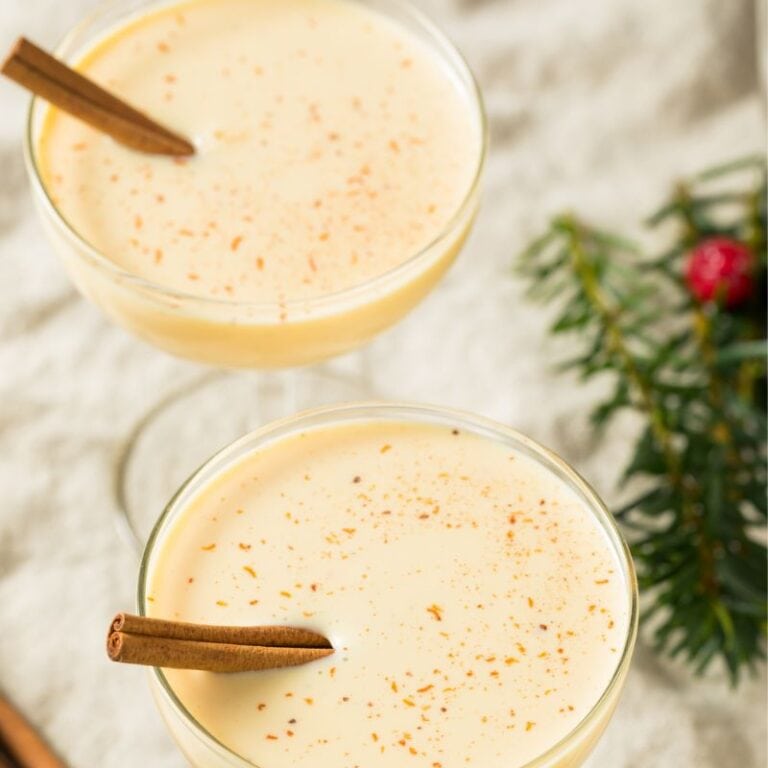 eggnog in martini glasses garnished with cinnamon sticks