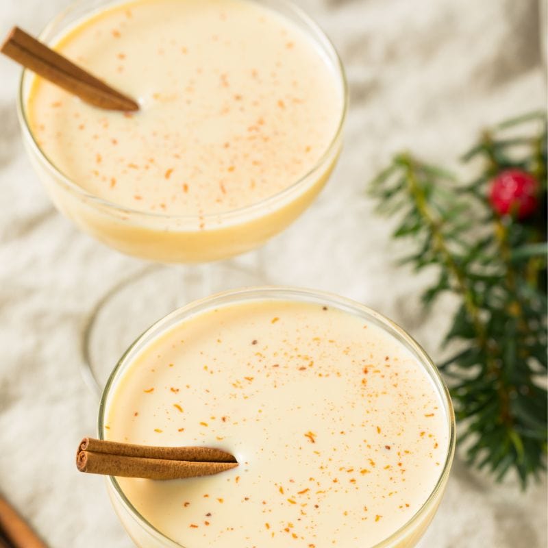 eggnog in martini glasses garnished with cinnamon sticks