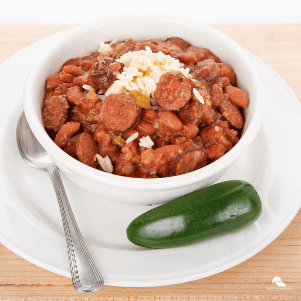 An image of red beans and rice in a white bowl, with a jalapeno on the side.
