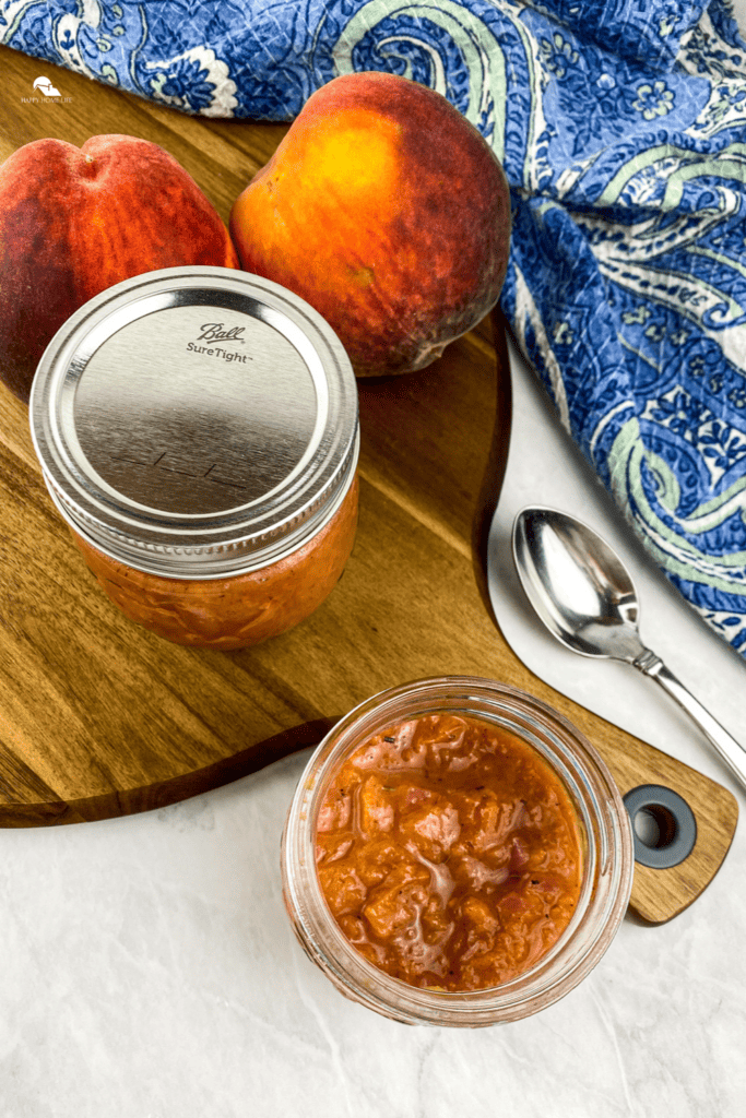 Savory Peach Compote in a jar on top of a wooden chopping board