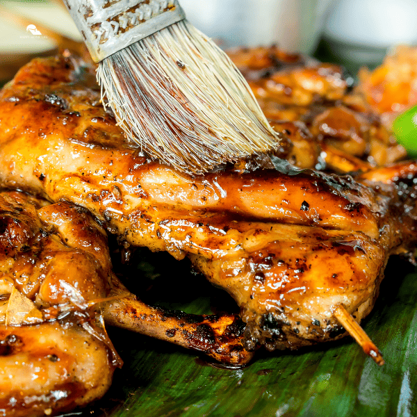 Applying marinade to juicy barbecued chicken with a brush. 