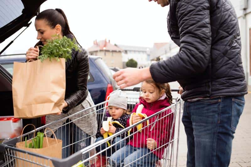 couple with kids putting groceries in car