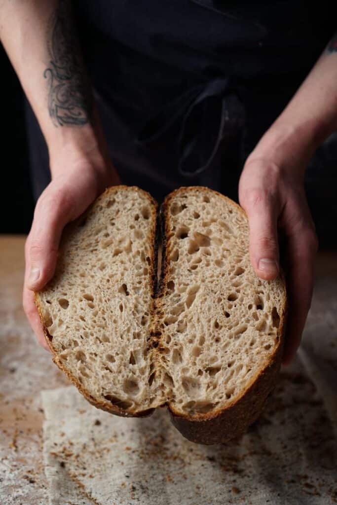 man's hands holding sourdough bread slices