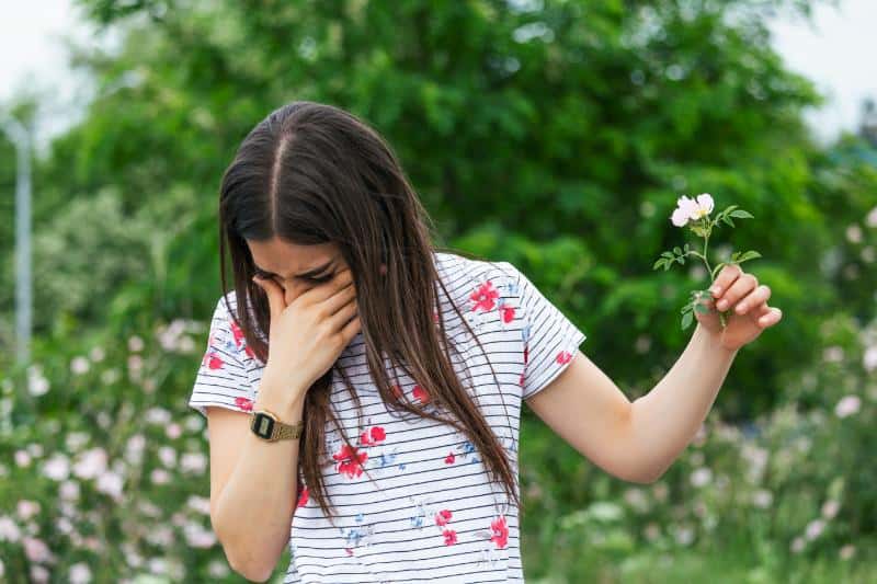 woman holding flower and sneezing