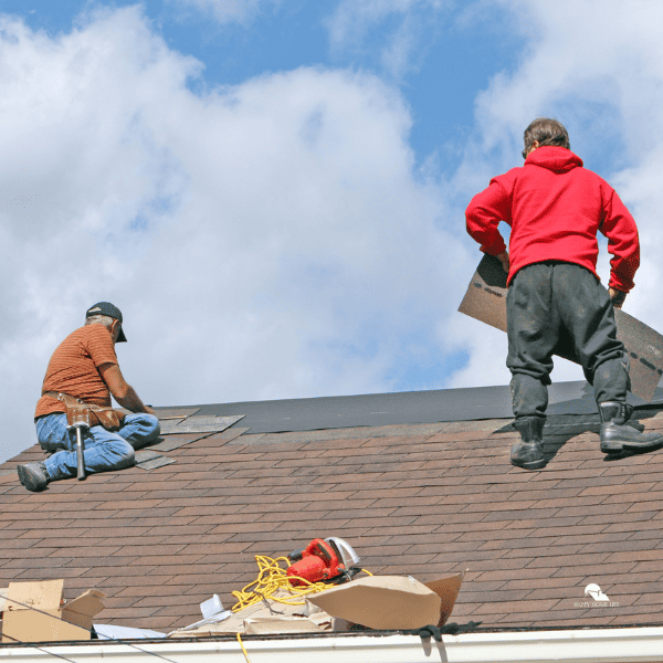 Two men replacing shingles on a house roof