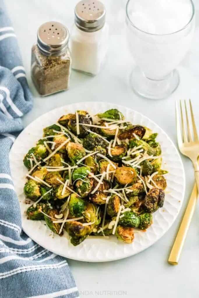 air fryer brussels sprouts on white plate with blue napkin to the left