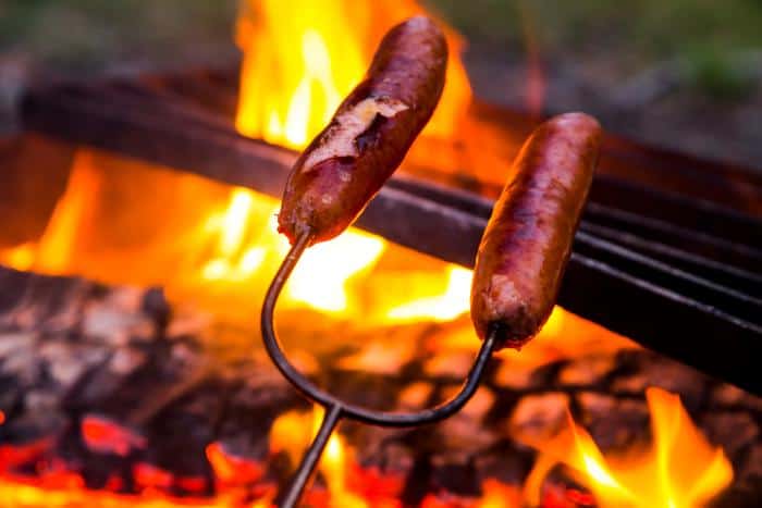 roasting sausages over a fire outdoors