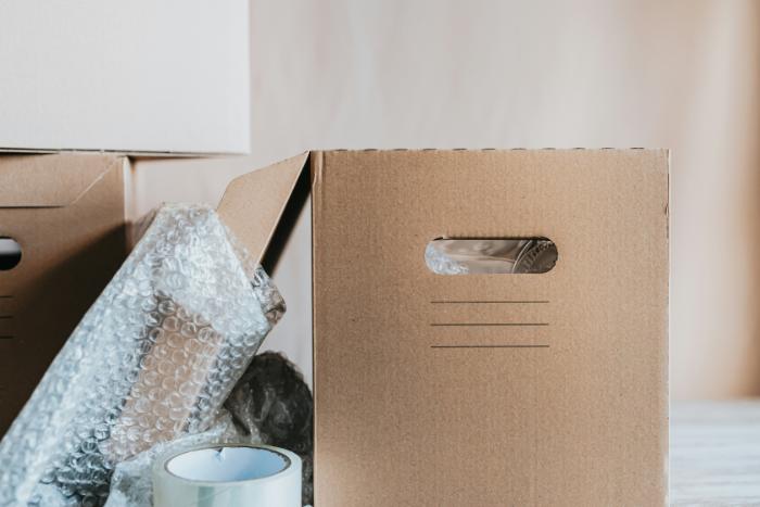 a moving box filled with items and beside the box is bubble wrap and packing tape