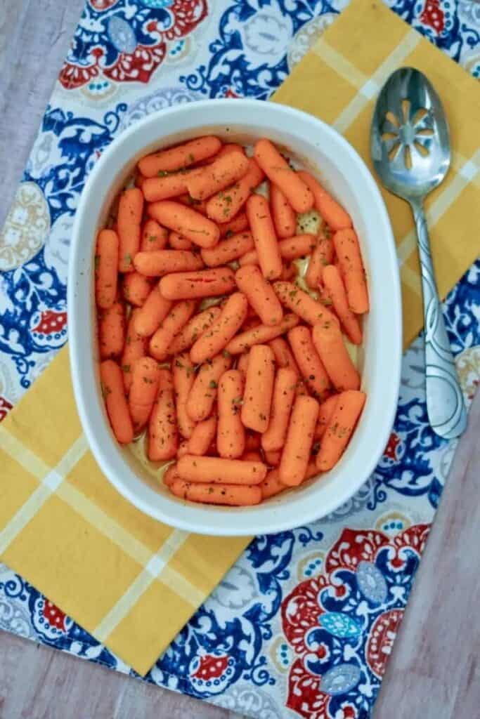 oven roasted baby carrots in a white baking dish on colorful napkins