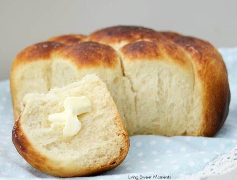 crock pot dinner rolls on a light blue napkin, one roll in front with a butter pat