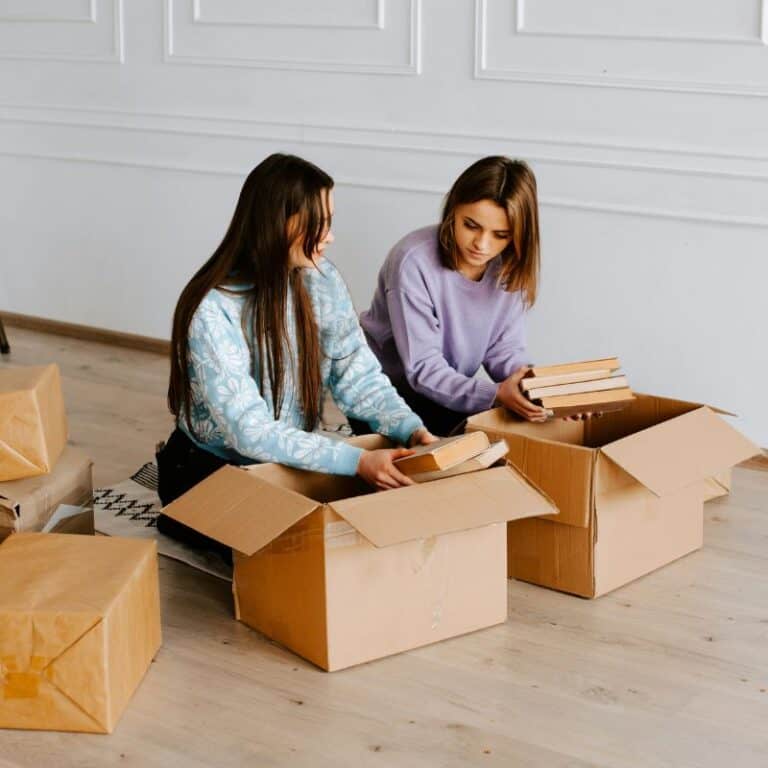two young women packing books into boxes