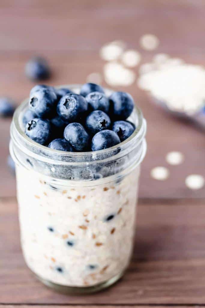 blueberry overnight oats in small jar on wooden background