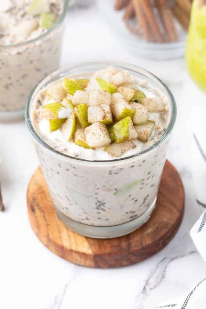 cinnamon pear overnight oats in glass on wooden coaster