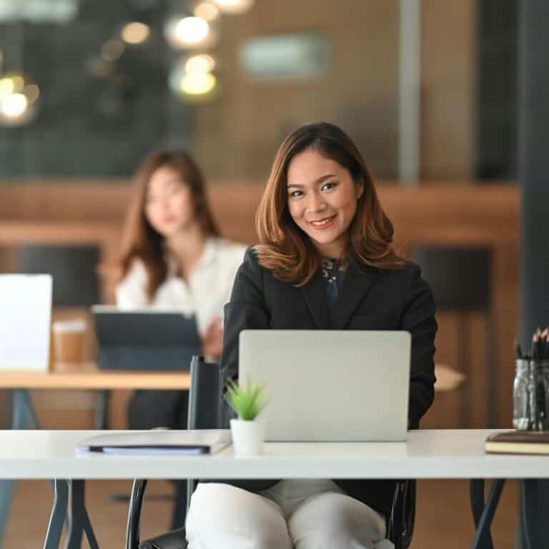 smiling and confident businesswoman at table with laptop