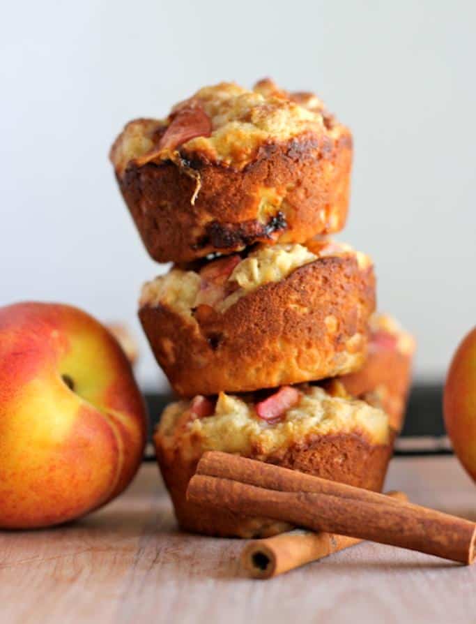 stacked peach oatmeal muffins with cinnamon sticks in front