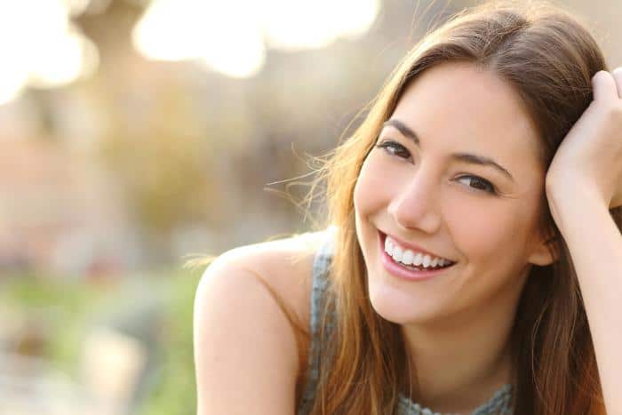 smiling woman with light brown hair and brown eyes outdoors