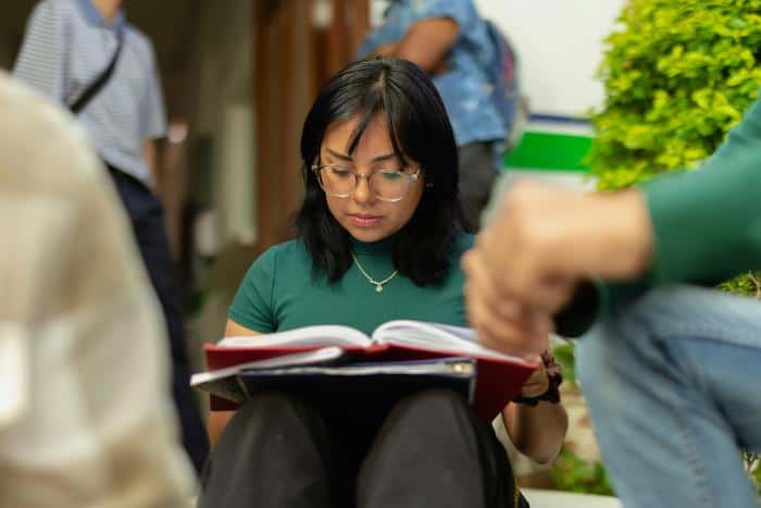 woman in green shirt sitting on steps with open book