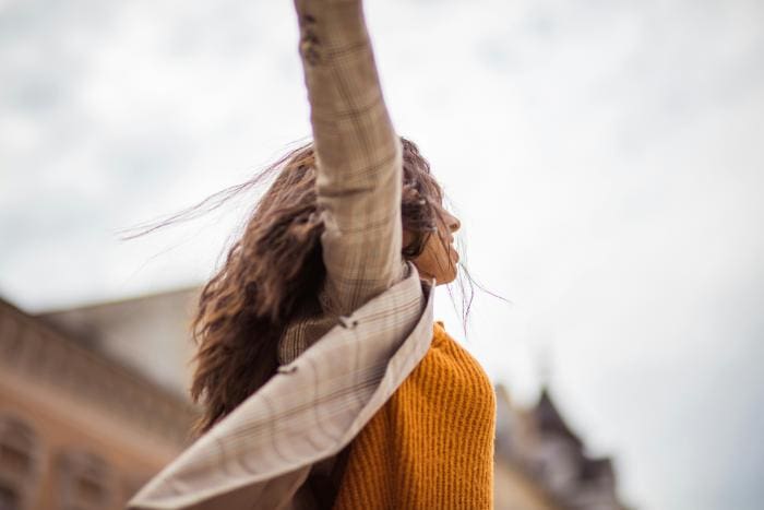 woman outdoors with arms raised in the air