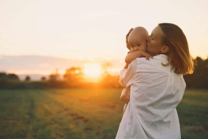 woman with baby outdoors with sun setting behind them