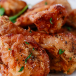 Close-up of crispy fried chicken pieces garnished with herbs and black pepper, showing golden brown texture perfect for a homemade crispy fried chicken dinner.