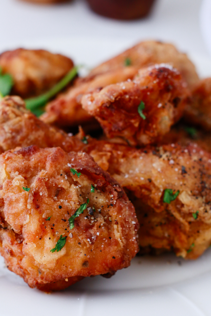 Close-up of crispy fried chicken pieces garnished with herbs and black pepper, showing golden brown texture perfect for a homemade crispy fried chicken dinner.