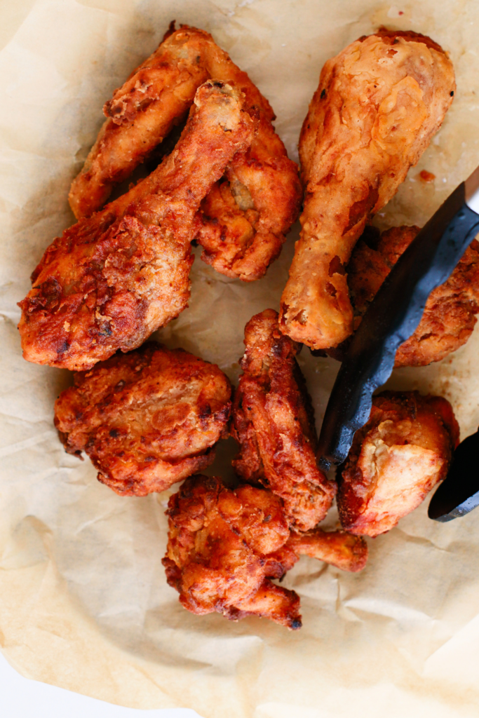 Golden, crispy homemade fried chicken pieces resting on parchment paper, showing crunchy texture and perfect browning for an easy fried chicken recipe made from scratch.