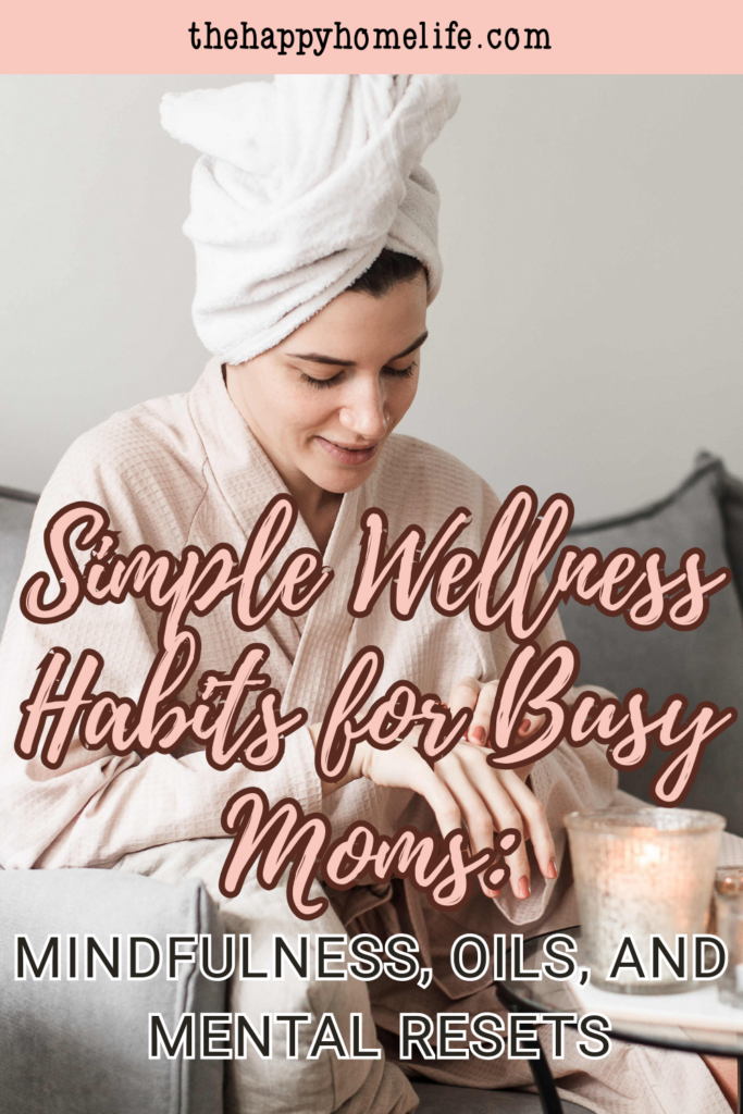 A woman in a bathrobe and towel turban applying essential oils while sitting at a table with a lit candle, as part of her wellness habit.